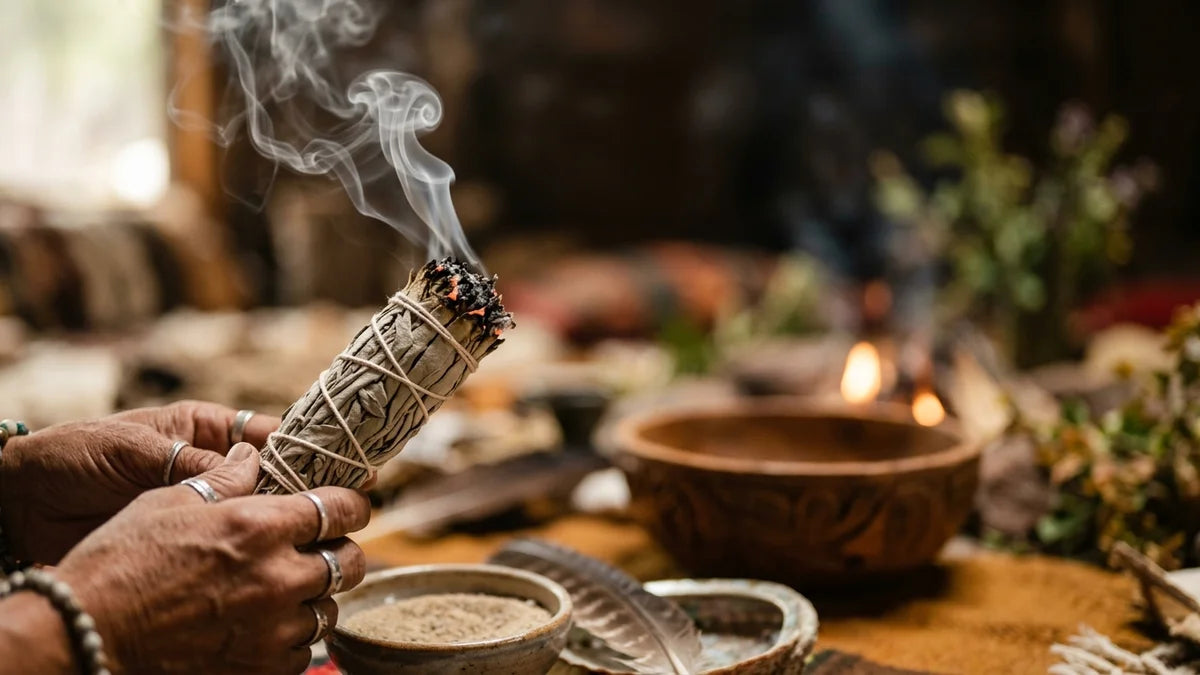 Fagot de sauge blanche fumant avec volutes de fumée sacrée lors d'un rituel spirituel
