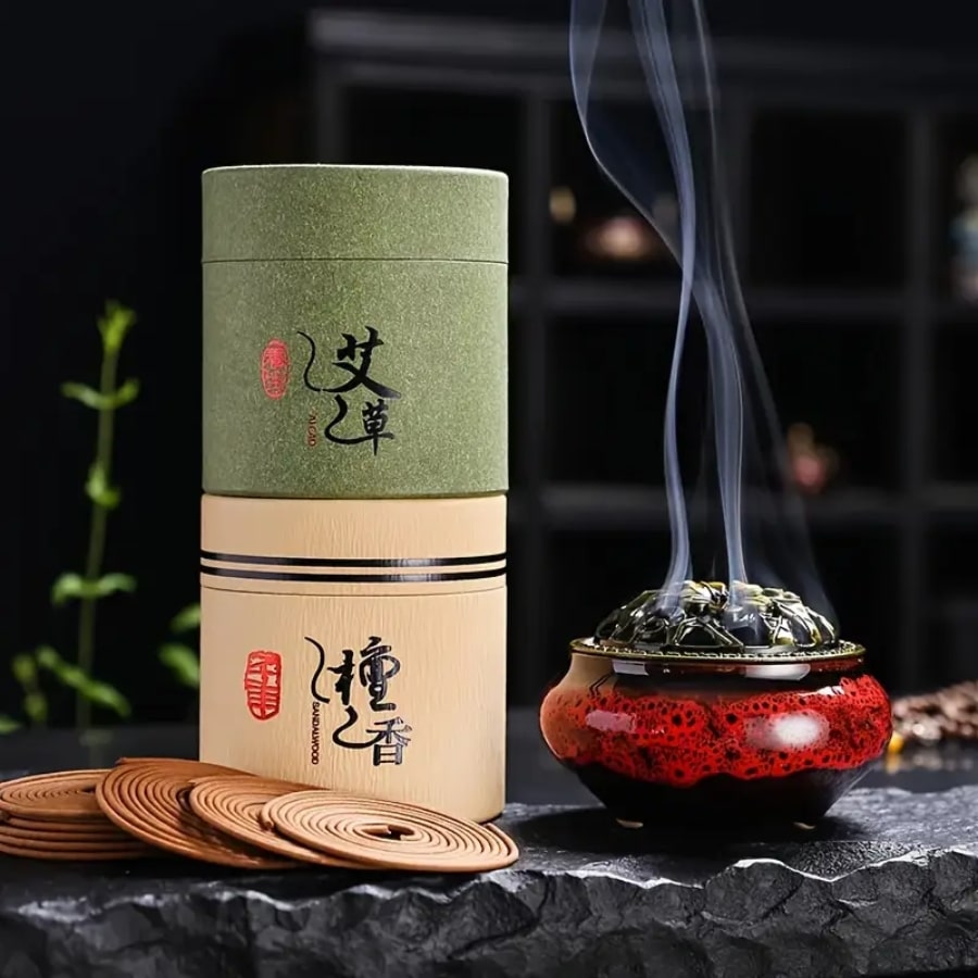 Deux boîtes d'encens en bobines posées l'une sur l'autre avec des spirales d'encens et un brûloir fumant sur une pierre noire