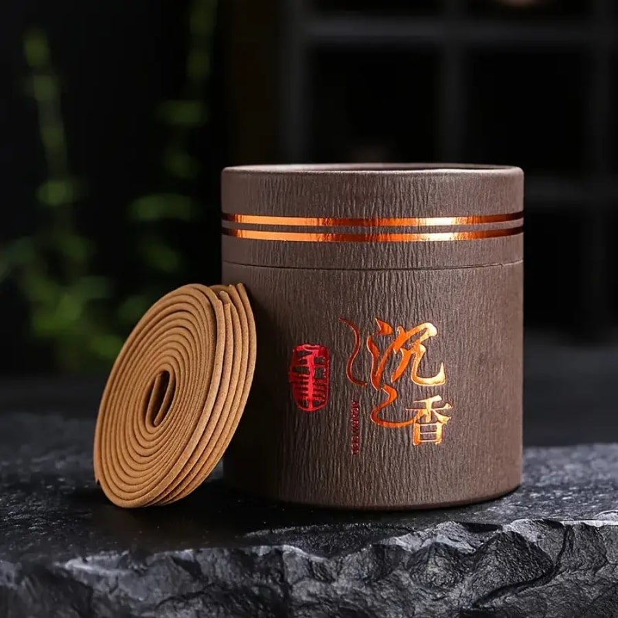 Une boîte d'encens en bobine bois d'agar avec une spirale posée sur une pierre noire