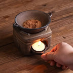 Un brûleur d'encens en céramique artisanal Effet pierre posé sur une table, en train de brûler du café