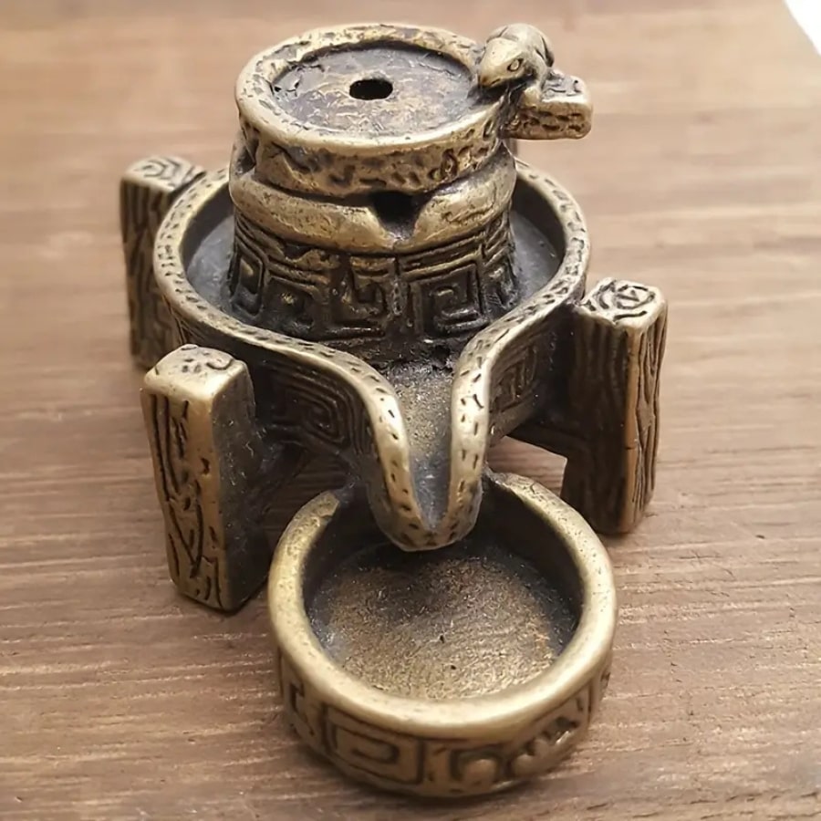 Un brûleur d'encens en cascade en bronze vu de face, avec une petite sculpture de dragon.