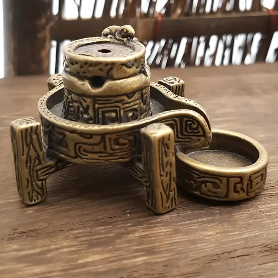 Un brûleur d'encens en cascade en bronze vu de côté, posé sur une table.