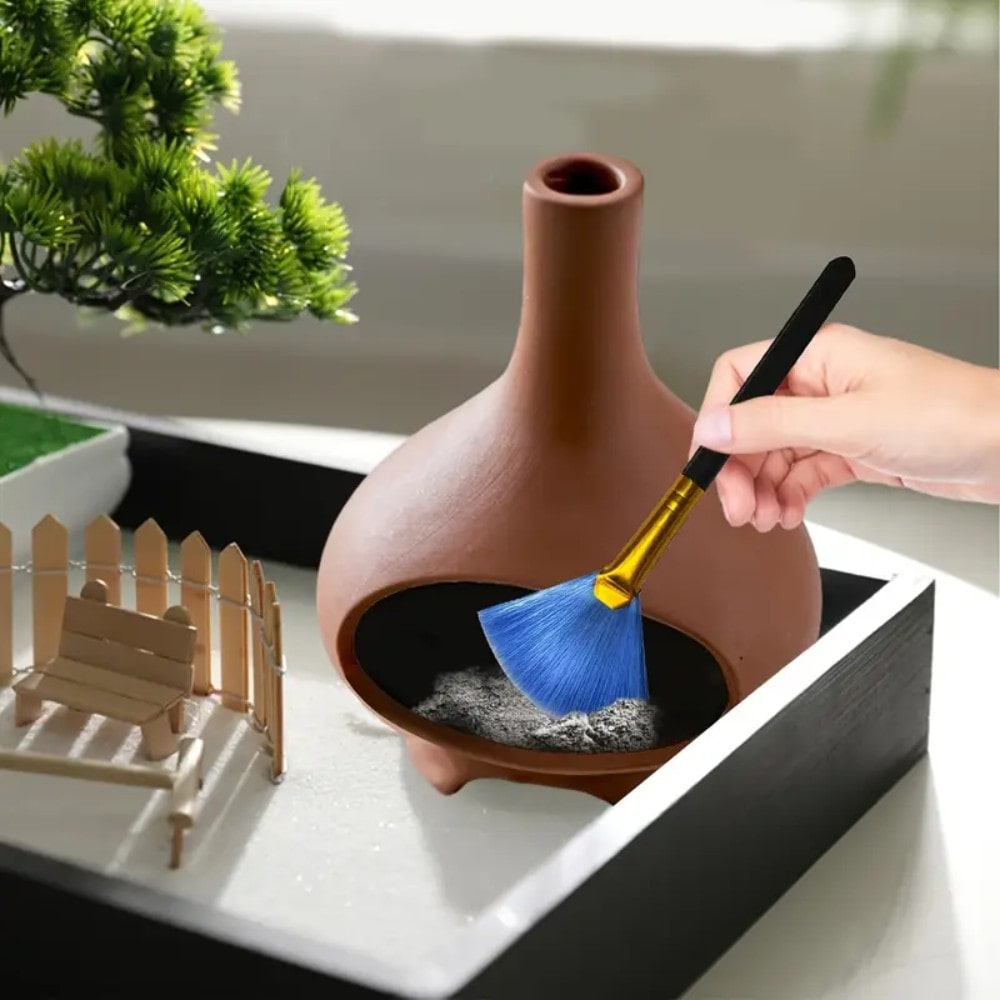 Photo d'une main en train d'espouster les cendres du brûleur d'encens pour Palo Santo en céramique couleur terre cuite