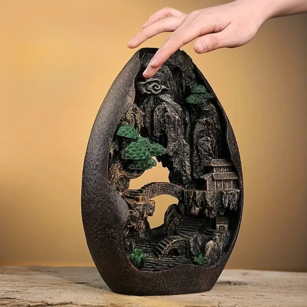 une main posée sur un brûleur d'encens à refoulement cascade montagne