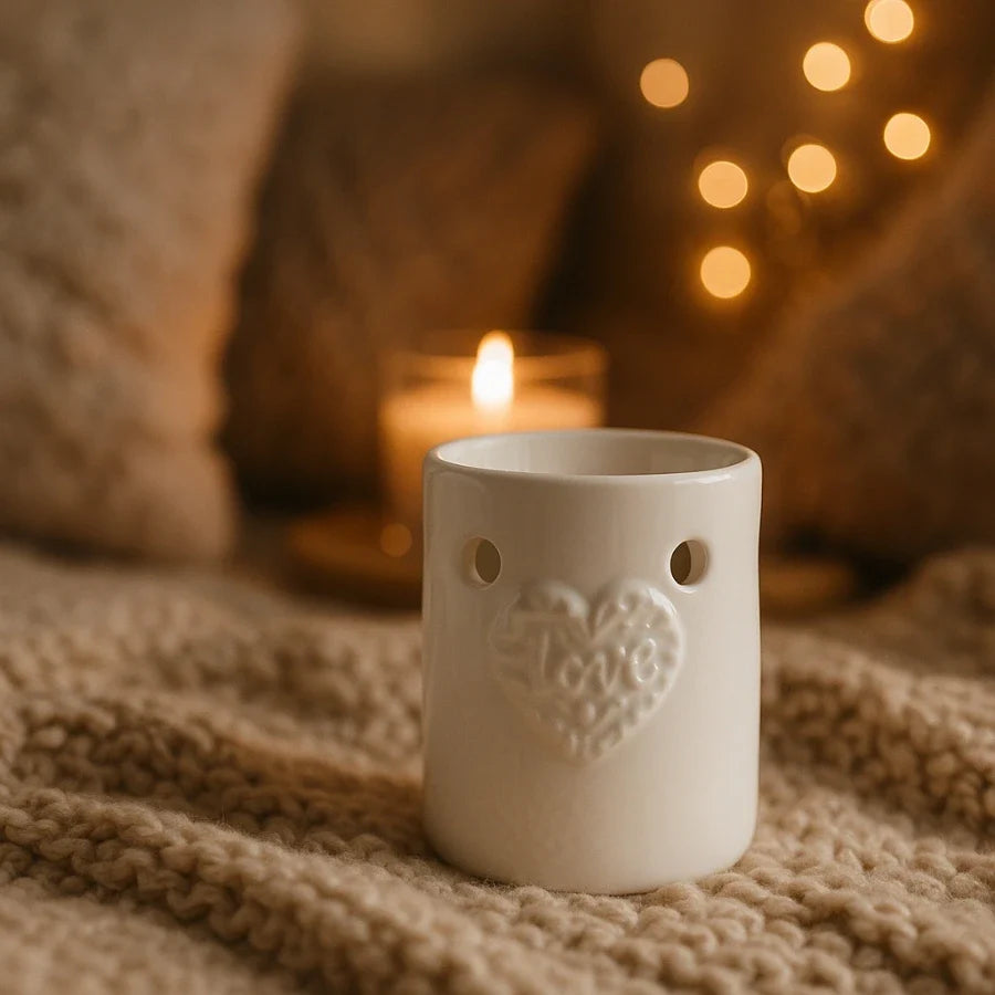 Un brûleur de carré d'ambre motif coeur blanc de la marque scentchips posé sur un plaid en laine