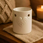Un brûleur de carré d'ambre de la marque scentchips motif coeur blanc posé sur un carré en laine