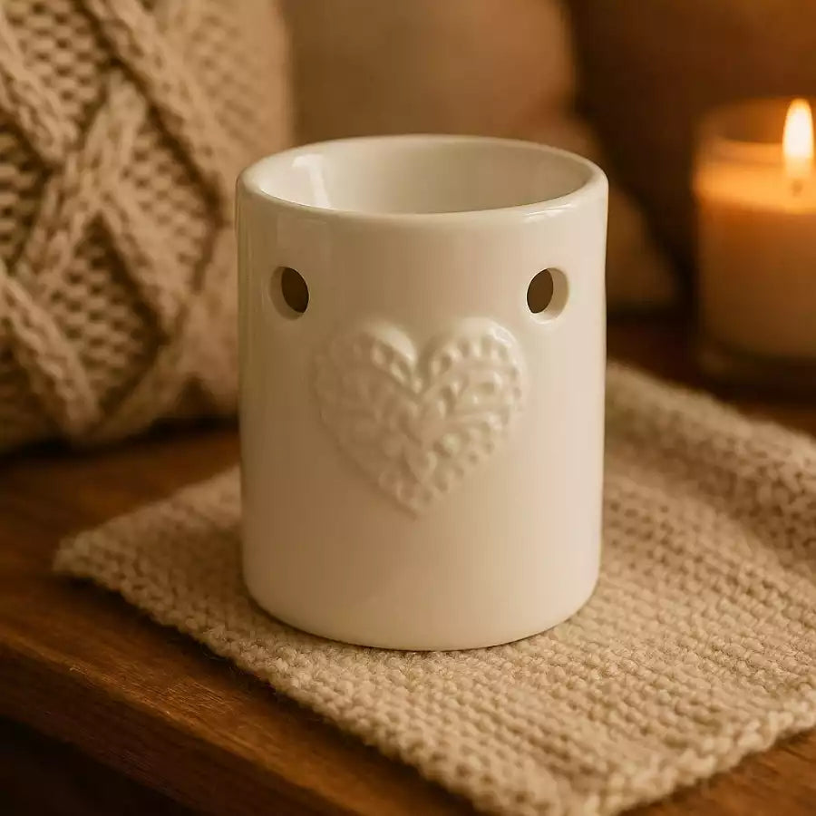 Un brûleur de carré d'ambre de la marque scentchips motif coeur blanc posé sur un carré en laine