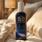 Brume d'oreiller Aromaspray 100 ml sur lit avec oreillers, packaging bleu marine et design plume