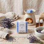 Packshot d'un paquet de quatre carrés fondants Drake à la senteur Lavande sur une table en bois devant un brule parfum