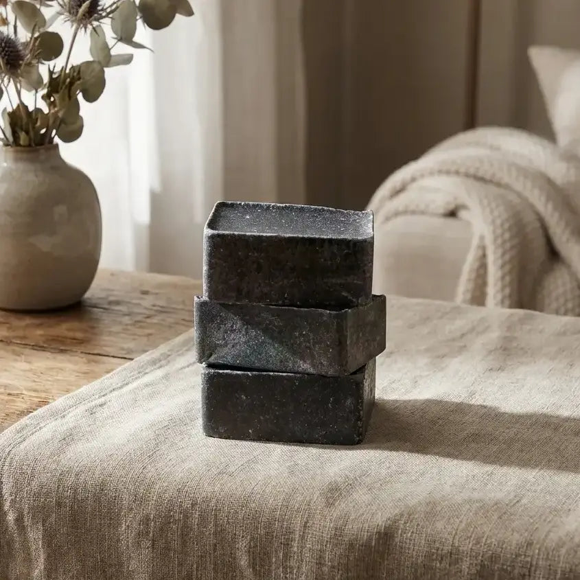 Carrés d'Ambre Musc Noir ByBazz empilés sur lin avec fleurs séchées et bois