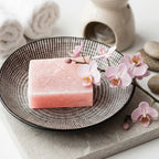 Carrés fondants orchidée rose HomeBreeze 50g dans bol noir avec fleurs orchidées