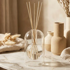 Diffuseur aromatique verre artisanal avec bâtons de roseaux sur marbre blanc