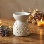 Diffuseur céramique artisanal blanc motif fleurs sur surface bois avec styling wellness