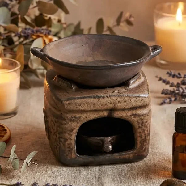 Diffuseur céramique rustique artisanal avec base pierre texturée et bol noir, entouré de botaniques séchées