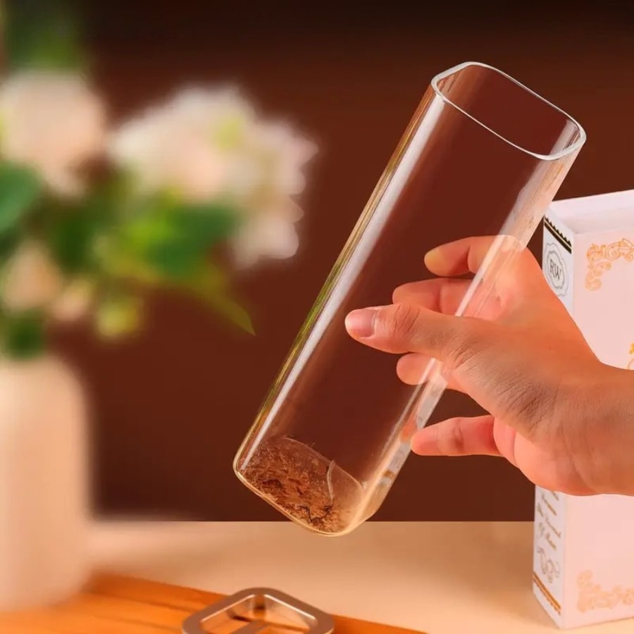 Une main portant un diffuseur d'encens en verre