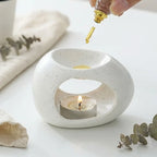 Diffuseur huiles essentielles céramique blanc artisanal avec gouttes d'huile dorées, style épuré minimaliste