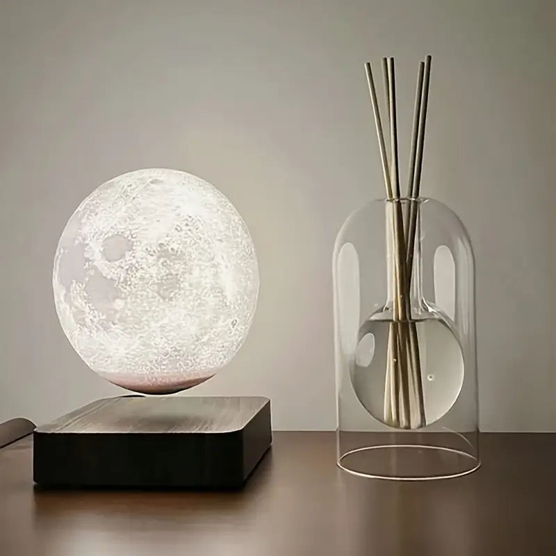 Un diffuseur de parfum en verre soufflé posé à côté d'une lampe lune