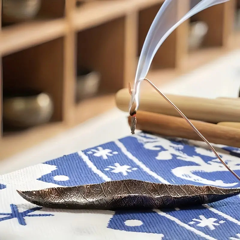 Un encens en corde parfum patchouli accroché à un porte encens et en train de bruler