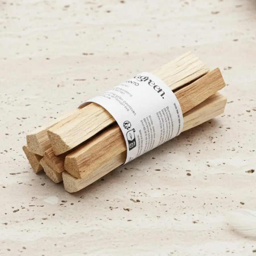 Un fagot de bâtons de palo santo de la maque Veegreen, sur une table en marbre beige mouchetée