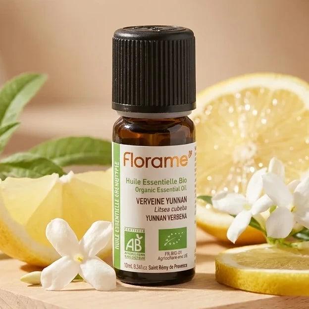 Flacon huile essentielle Verveine Yunnan Bio Florame 10ml entouré de citrons et fleurs blanches