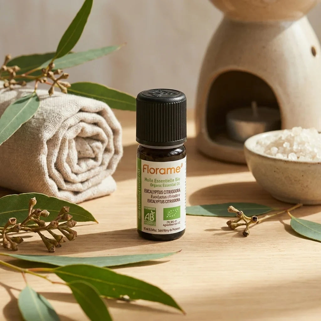 Flacon Huile Essentielle d'Eucalyptus Citriodora Bio Florame 10ml sur surface bois avec feuilles
