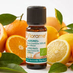 Huile essentielle agrumes bio Florame 10ml entourée d'agrumes frais et feuilles vertes