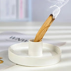 Un Porte-Bâton de Palo Santo et Sauge de forme ronde avec un baton de palo santo en train de bruler