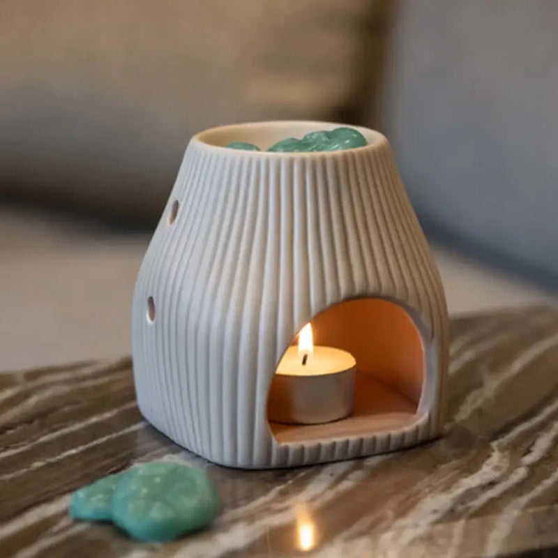 Un bruleur de fondants parfumés de la marque Scentchips posé sur une table en marbre, avec une bougie chauffre-plat allumée à l'intérieur