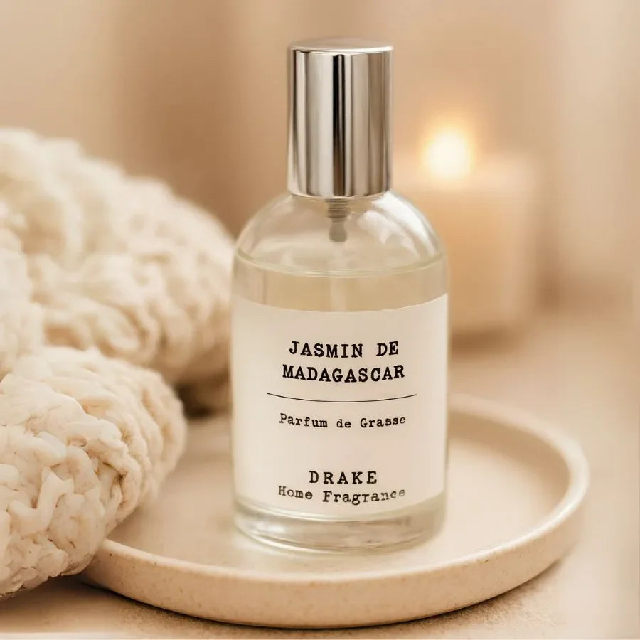 Un spray d'ambiance jasmin de madagascar de la marque Drake posé sur un support en marbre avec un plaid en laine
